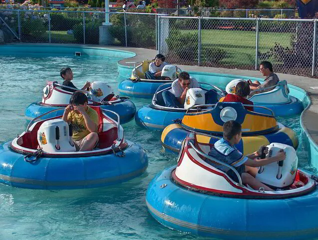 A group of children and adults riding bumper boats in a pool
